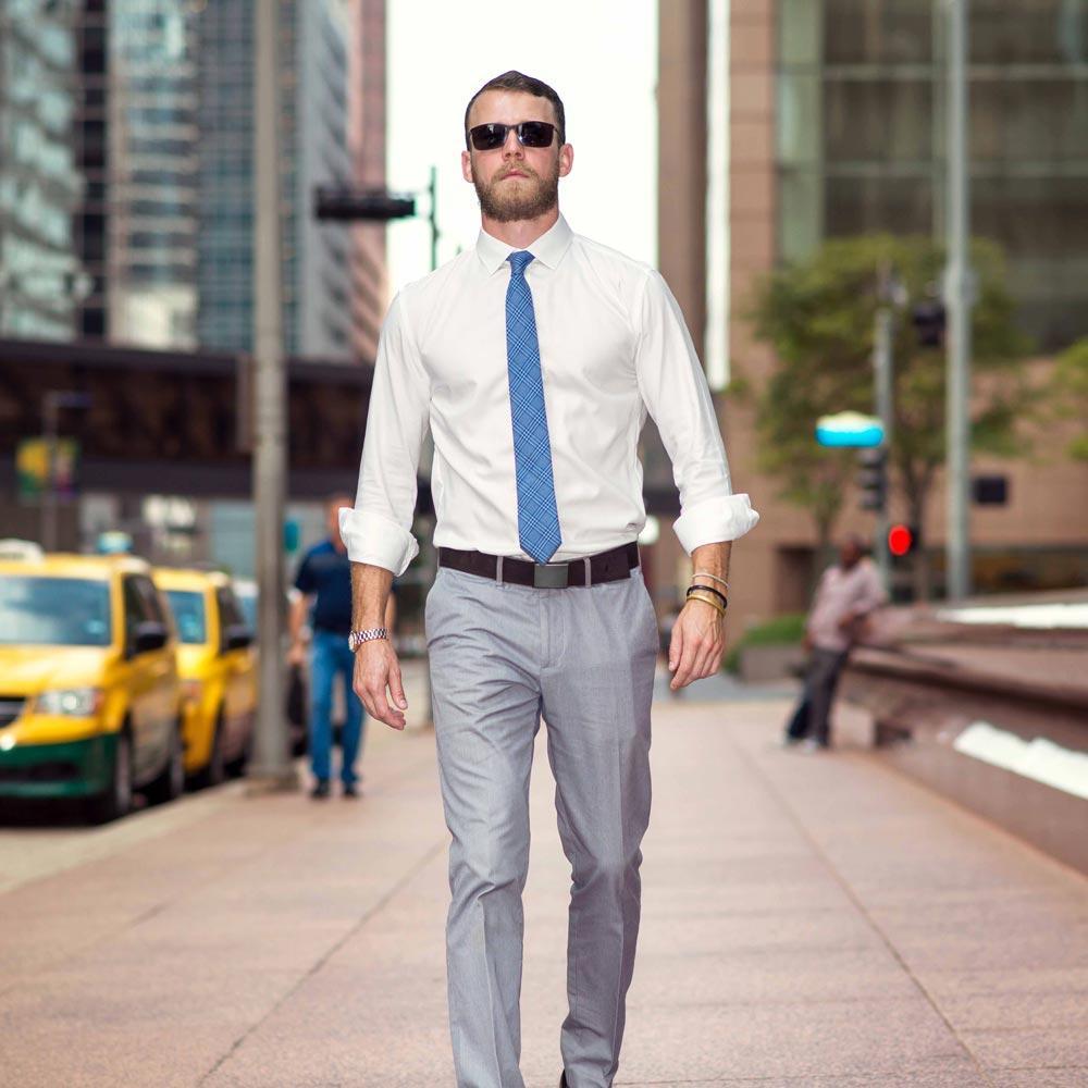 Man in formal attire walking on a city street with taxis in the background