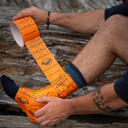 Person wearing orange socks with black patterns sitting on a wooden surface