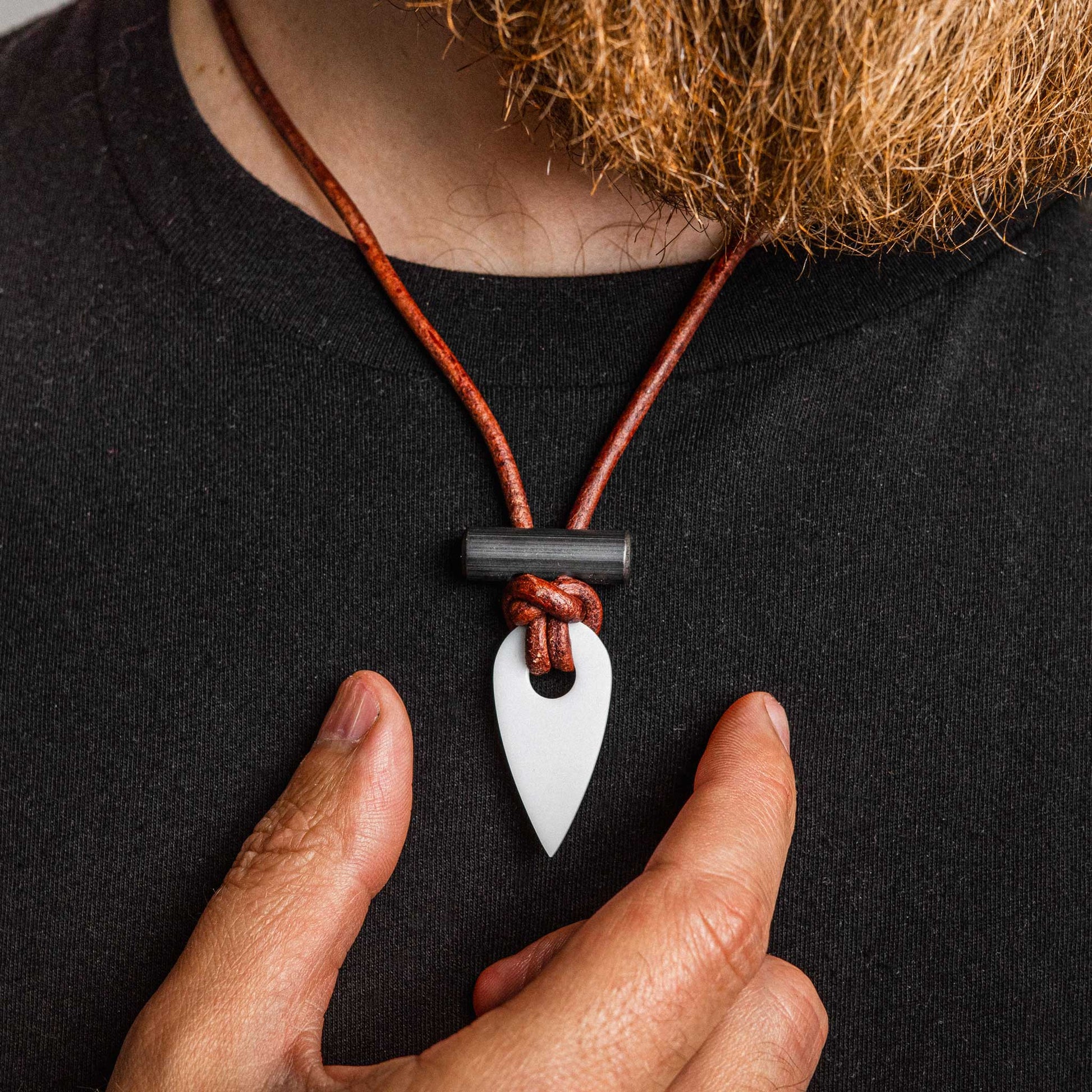 Person wearing a necklace with a white pendant on a black background
